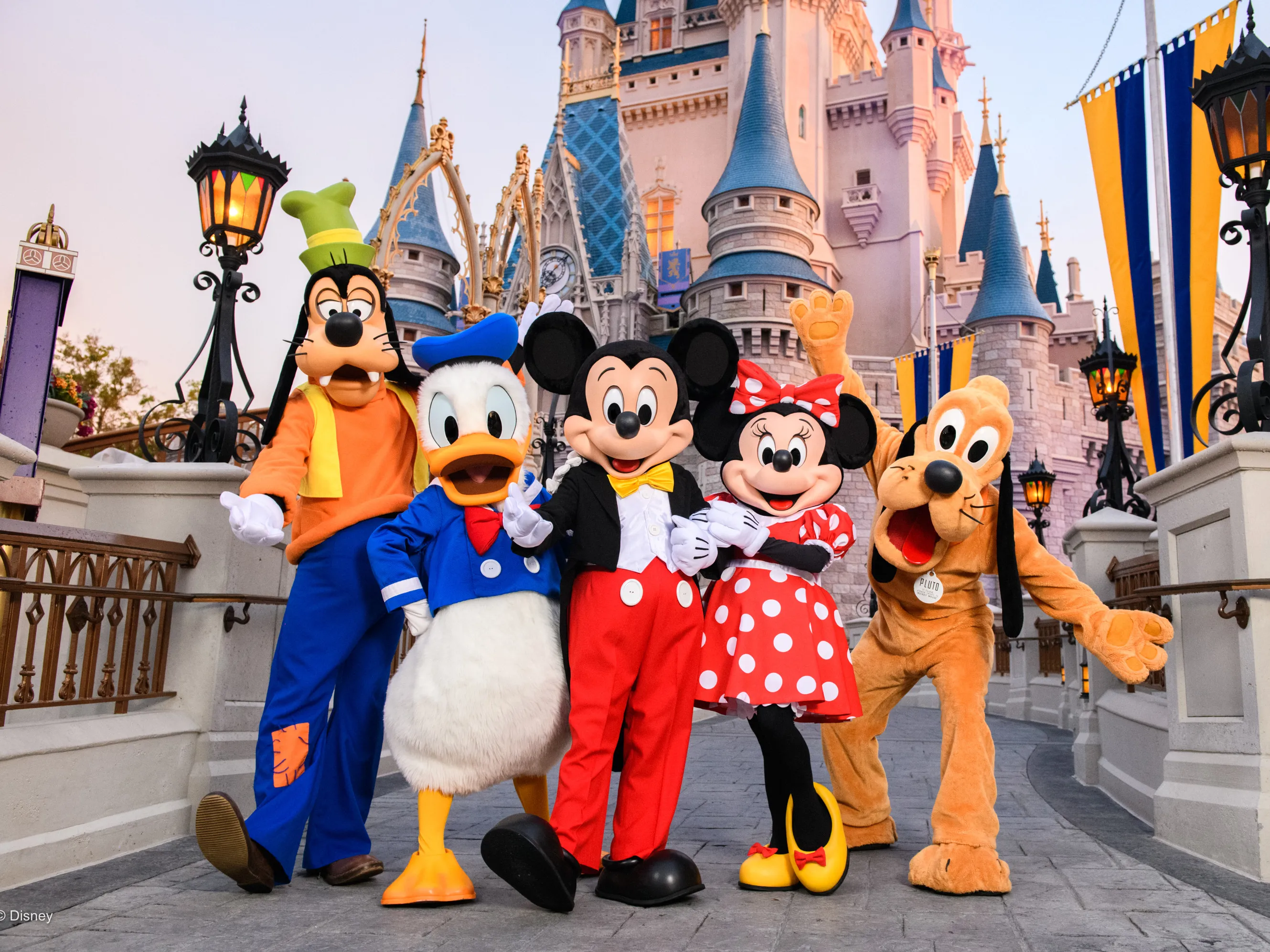 Disney characters standing in front of the Magic Kingdom castle